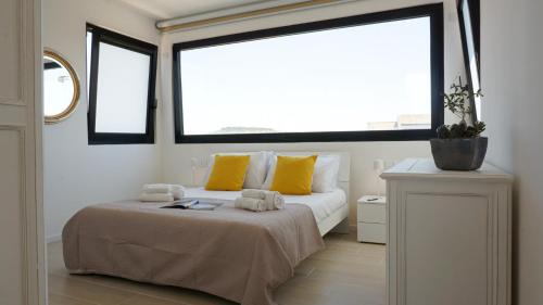 a bedroom with a bed with yellow pillows and a window at Postcard in Alghero