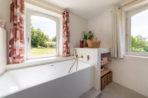 La salle de bains est pourvue d'une baignoire et de 2 fenêtres. dans l'établissement Gîte de Fompesquiere, à Frespech