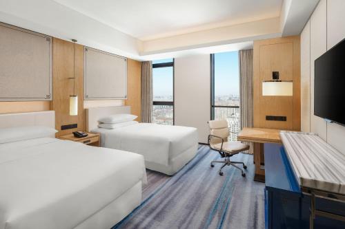 a hotel room with two beds and a desk and a television at Sheraton Zibo Hotel in Zibo