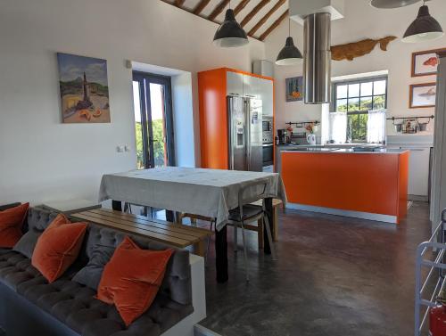 eine Küche und ein Wohnzimmer mit einem Sofa und einem Tisch in der Unterkunft Casa Baleia Laranja Ocean-Front in Cabeço Chão