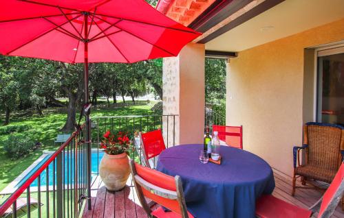 einen Tisch mit einem roten Regenschirm auf einer Veranda in der Unterkunft Beautiful Home In Colonzelle in Colonzelle