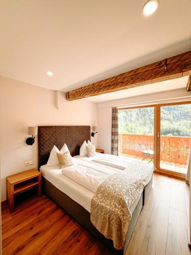 a bedroom with a large bed and a large window at Hotel Pass Lueg in Golling an der Salzach