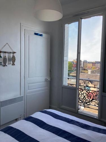 une chambre avec un lit et une grande fenêtre dans l'établissement Appartement cosy vue mer, au Tréport