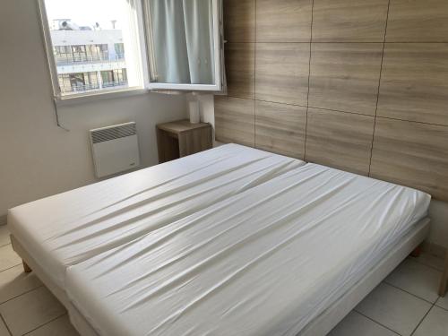 un lit blanc dans une chambre avec une fenêtre dans l'établissement Sol-y-Days Cap Camargue duplex et piscine, au Grau-du-Roi