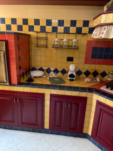 a kitchen with red cabinets and colorful tiles at Casa Ale in Avola