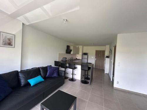 un salon avec un canapé noir et une cuisine dans l'établissement Duplex Neuf et Cosy avec Place Parking, à Plan-de-Cuques