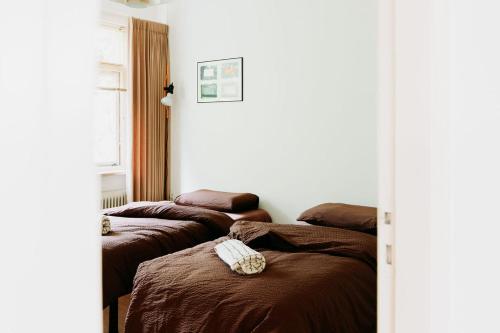 een kamer met 3 bedden en bruine dekens bij Bungalowvilla Robin Hill, met bostuin & design interieur in Haelen