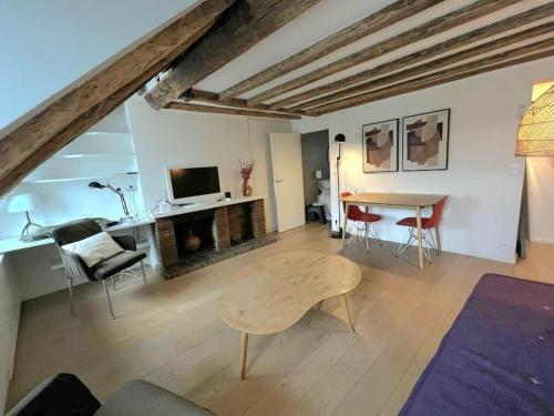 un salon avec une table, des chaises et une télévision dans l'établissement Elegant Loft Place Vendôme, à Paris