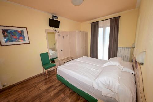 a bedroom with a white bed and a green chair at Hotel La Fenice e Sole in Tremosine Sul Garda