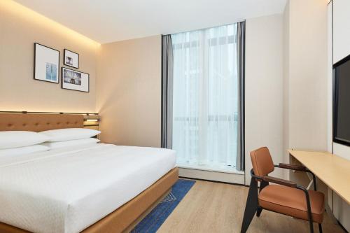 a hotel room with a bed and a desk and a window at Four Points by Sheraton Chengdu, High-Tech Zone Exhibition Center in Chengdu