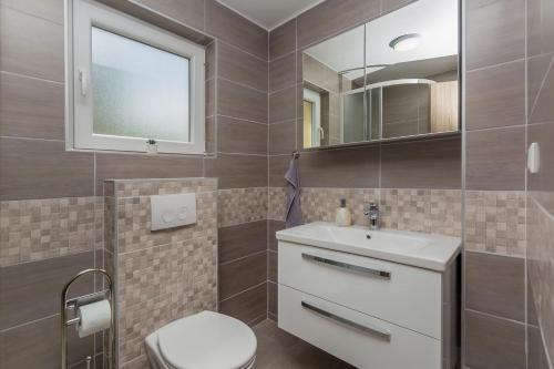 a bathroom with a toilet and a sink and a mirror at Apartmani Tena in Njivice