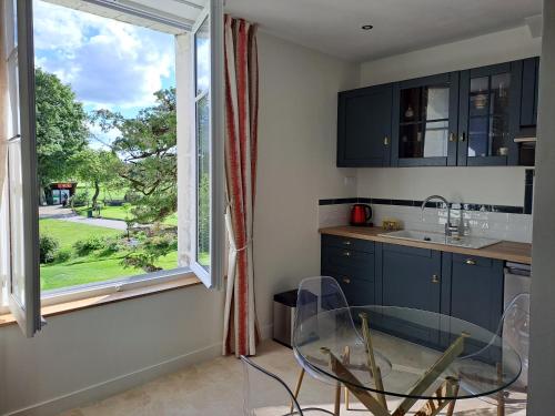 une cuisine avec une table en verre et une fenêtre dans l'établissement Le Relais du Golf- Château de la Touche, à Ballan-Miré