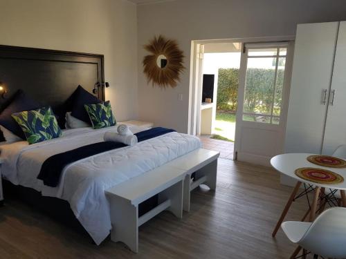 a bedroom with a large bed and a table at Cute condo with garden and BBQ in Plettenberg Bay