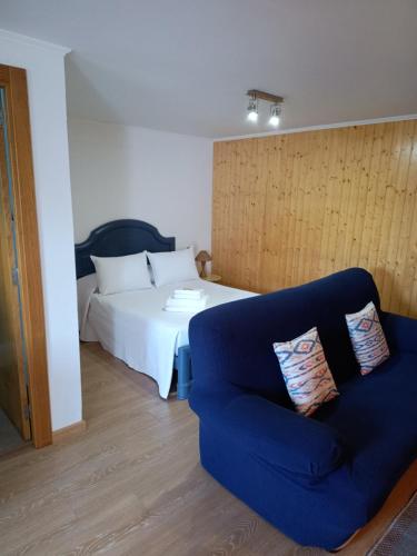 a bedroom with a bed and a blue couch at Playa de Seiruga in Malpica