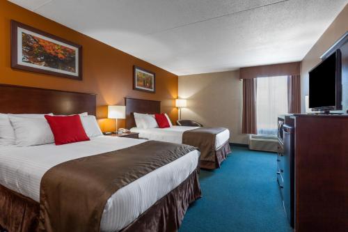 a hotel room with two beds and a flat screen tv at Ramada by Wyndham Timmins in Timmins