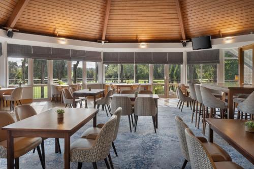 a restaurant with tables and chairs and windows at Delta Hotels by Marriott Tudor Park Country Club in Maidstone