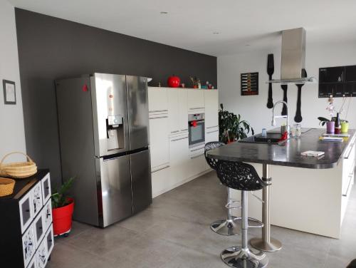 une cuisine avec un réfrigérateur en acier inoxydable et une table dans l'établissement Très belle maison avec SPA extérieur, à Nozay