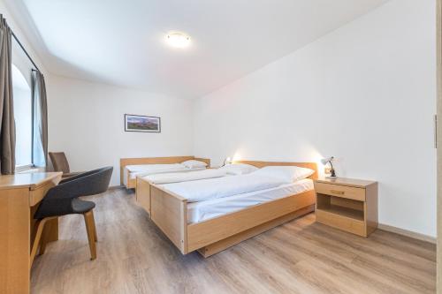 a room with three beds and a desk and a desk at Central Apartments Cristlpek in Ortisei
