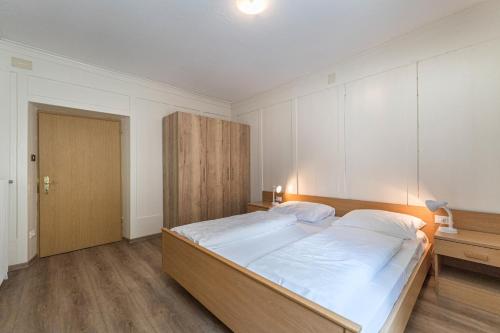 a bedroom with a large bed with white sheets at Central Apartments Cristlpek in Ortisei