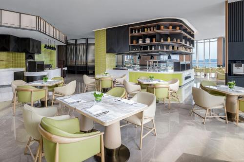 a restaurant with tables and chairs in a room at Qingdao Marriott Hotel Jiaozhou in Qingdao