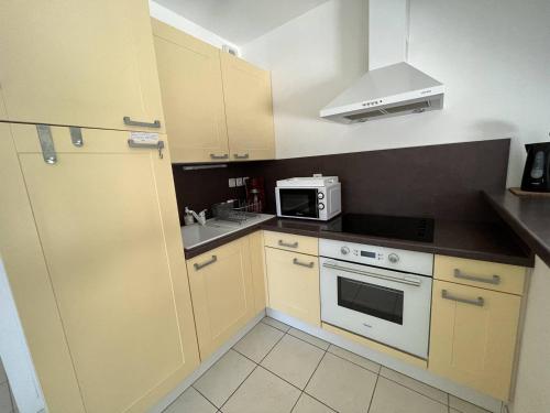 une petite cuisine avec des armoires jaunes et un appareil blanc dans l'établissement Charmante Maison de Vacances avec Piscine, Proche Plage et Commerces - FR-1-324A-43, à Notre-Dame-de-Monts
