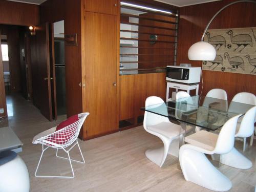 une salle à manger avec une table en verre et des chaises blanches dans l'établissement Appartement 3 pièces avec clim, wifi, parking Saint-Cyprien Plage - FR-1-106-62, à Saint-Cyprien