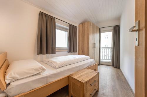 a small bedroom with a bed and a window at Central Apartments Cristlpek in Ortisei