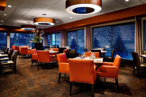 a dining room with tables and chairs and windows at Delta Hotels by Marriott Sault Ste. Marie Waterfront in Sault Ste. Marie
