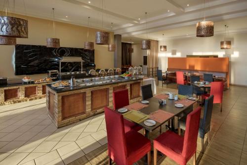 a dining room with a table and red chairs at Protea Hotel by Marriott Chipata in Chipata