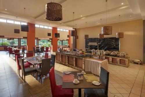 a restaurant with tables and chairs and a kitchen at Protea Hotel by Marriott Chipata in Chipata