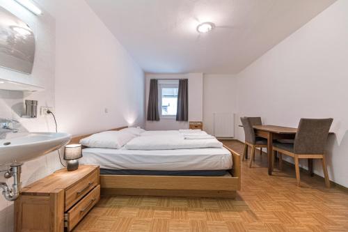 a bedroom with a bed and a sink and a table at Central Apartments Cristlpek in Ortisei