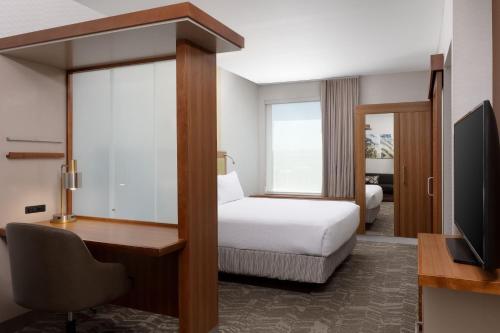 a hotel room with a bed and a desk and a tv at SpringHill Suites by Marriott Grand Junction Downtown/Historic Main Street in Grand Junction