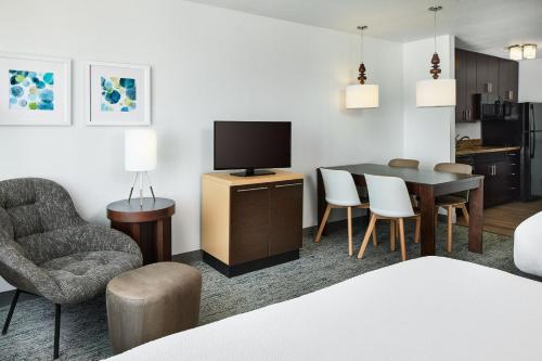 a living room with a television and a table and chairs at TownePlace Suites by Marriott Garden City in Garden City