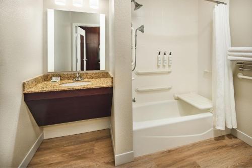 a bathroom with a sink and a tub and a mirror at TownePlace Suites by Marriott Garden City in Garden City