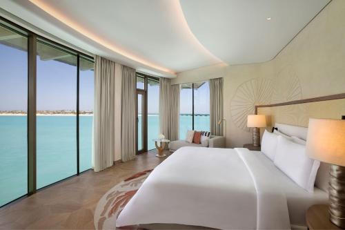 a bedroom with a large white bed and large windows at The St. Regis Red Sea Resort in Ḩanak