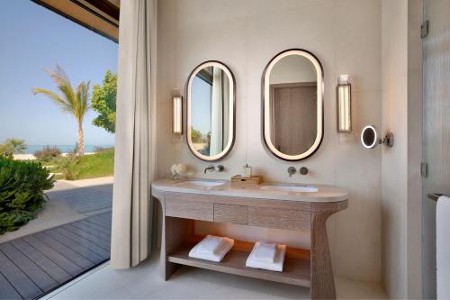 a bathroom with a sink and two mirrors at The St. Regis Red Sea Resort in Ḩanak