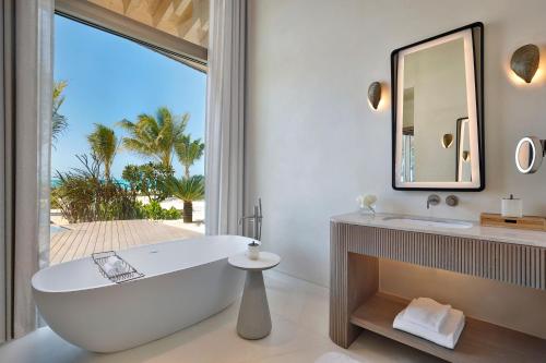 a bathroom with a tub and a sink and a mirror at The St. Regis Red Sea Resort in Ḩanak