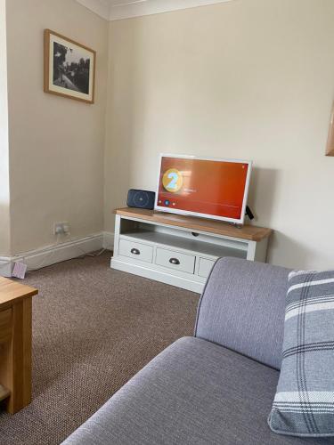 a living room with a couch and a flat screen tv at Relaxing Riverside Retreat, Ross on Wye in Ross on Wye
