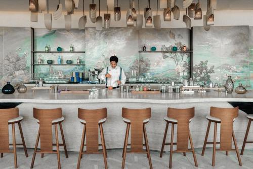 a man standing behind a bar in a restaurant at The St. Regis Red Sea Resort in Ḩanak