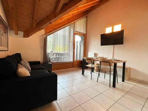 un salon avec un canapé noir et une table dans l'établissement Appartement T2 au centre de Samoëns avec parking, animaux acceptés - FR-1-624-43, à Samoëns