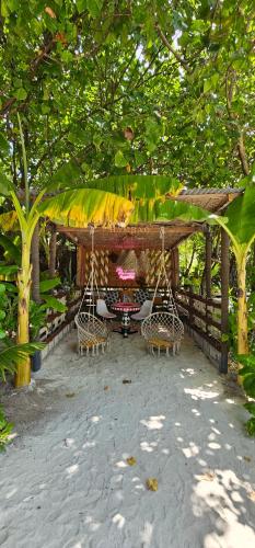 a patio with chairs and a table under a roof at Chambao Maldives in Guraidhoo