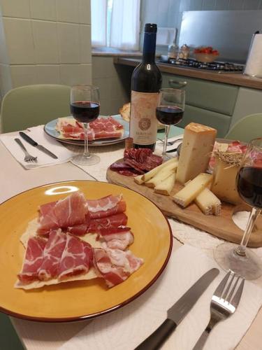 a table with a plate of meat and cheese and wine at La Pintadera Sarda in Carbonia