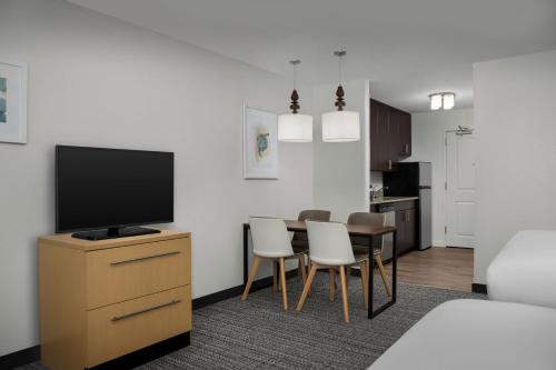 a living room with a television and a table with chairs at TownePlace Suites by Marriott Gainesville Northwest in Gainesville
