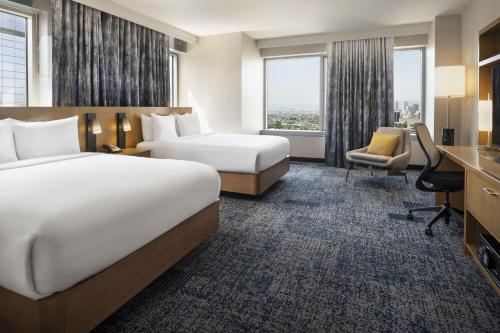 a hotel room with two beds and a desk at Courtyard by Marriott Los Angeles L.A. LIVE in Los Angeles