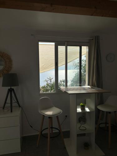 une pièce avec une table et deux tabourets et une fenêtre dans l'établissement Appartement bord de mer 2 personnes, à Sagone