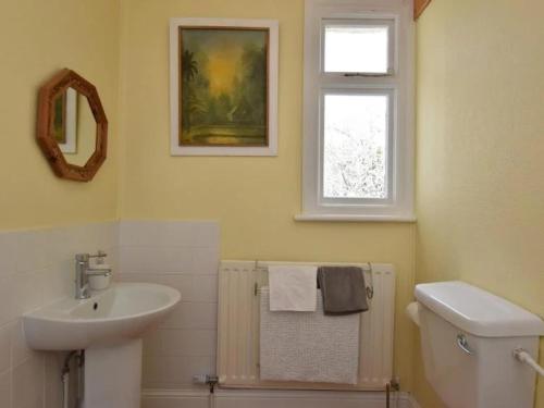 a bathroom with a sink and a toilet and a window at Spectacular Sea View Retreat in Lanteglos
