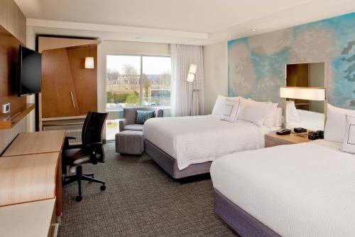 a hotel room with two beds and a desk at Courtyard by Marriott Yonkers Westchester County in Yonkers