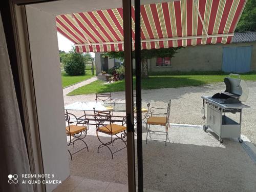 a patio with a grill and tables and chairs at La Maison du Gaillard in Chitenay