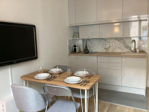 Il comprend une cuisine avec une table en bois, des chaises et une télévision. dans l'établissement Cocon chic parisien niché au cœur de Montmartre, à Paris
