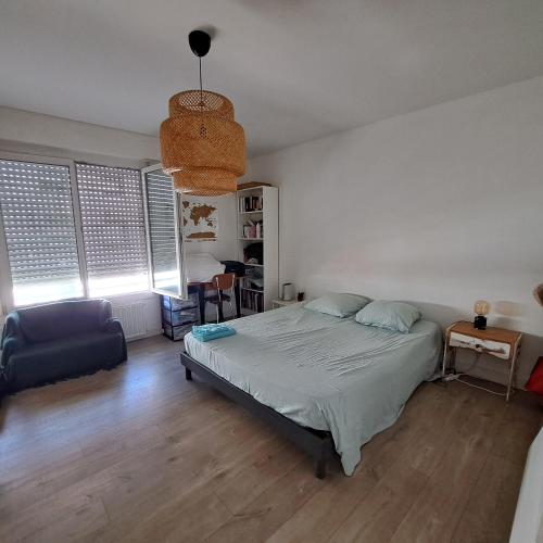 une chambre avec un lit, une chaise et des fenêtres dans l'établissement Maison de ville front de mer, à Saint-Nazaire